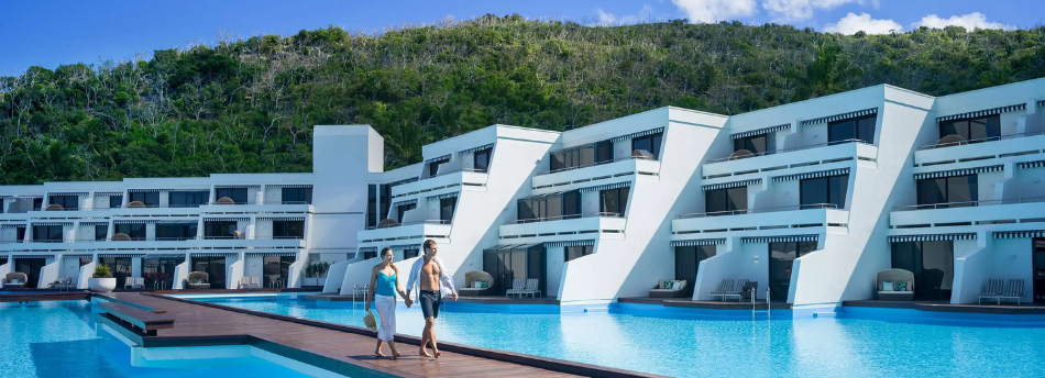 Couple walking hand in hand through the pool on a luxury beach resort 